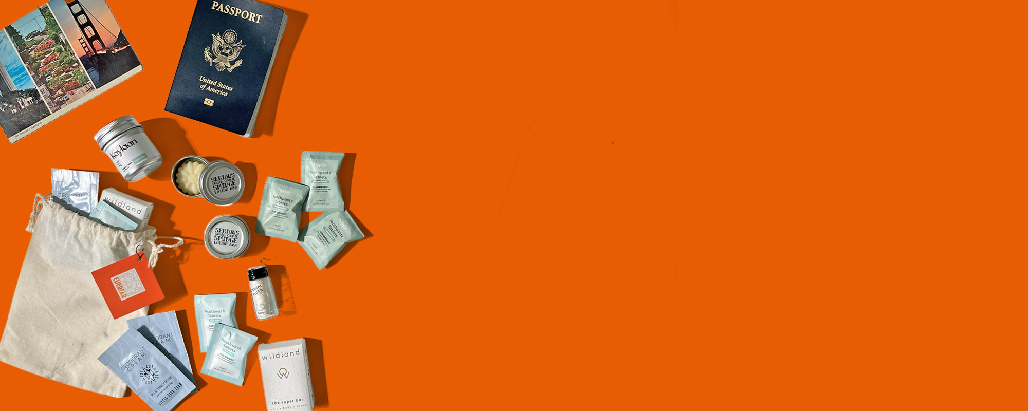 Collection of travel items including a passport, travel-sized toiletries, and a bag on an orange background